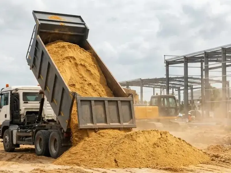 Caminhão basculante descarregando areia em obra