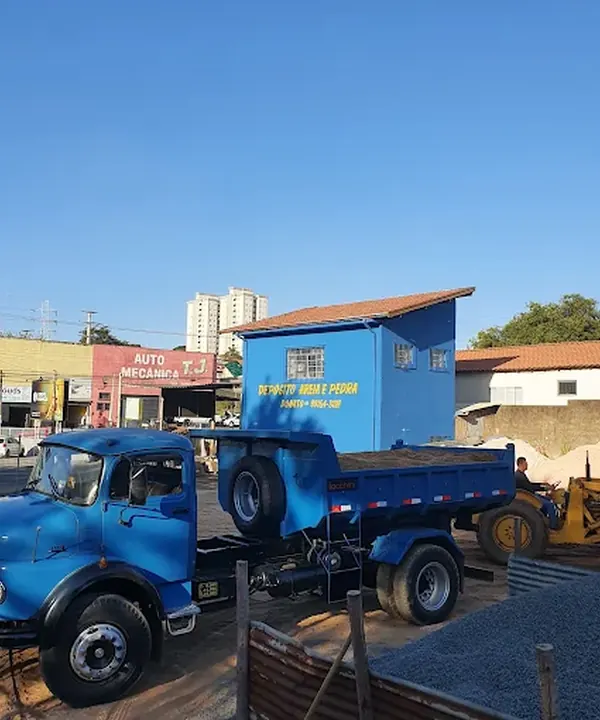Caminhão basculante azul da Donato em frente ao depósito